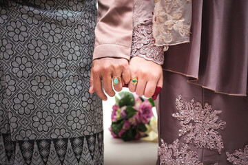 Malay wedding theme, holding hands newlyweds. Beautiful young adult couple.