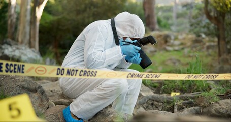 Forensic, photographer and police tape at crime scene for investigation in forest with evidence and...