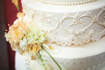 Five-tiered elegant white wedding cake decorated with flowers on a table. Wedding decoration cake. Selective focus.