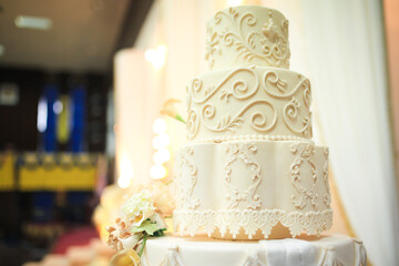 Five-tiered elegant white wedding cake decorated with flowers on a table. Wedding decoration cake....