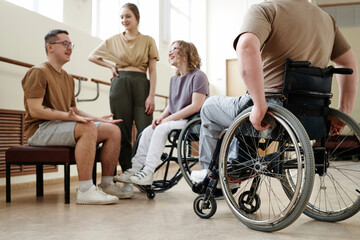 Low angle view selective focus shot of wheelchair dancers and their partners relaxing and chatting during break
