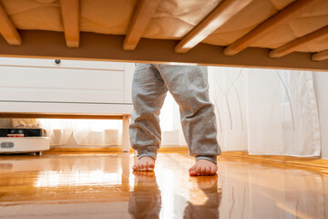 Baby standing firmly barefoot in a crib photographed from the floor. Hidden frame concept