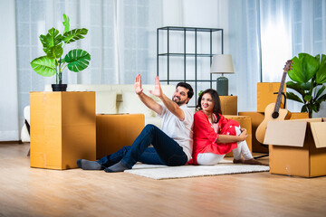 Home shifting or moving with indian young couple sitting on flore surrounded by cardboard boxes