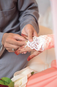 Groom put a ring on finger of his lovely wife. Close up image and selective focus.