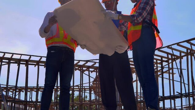 Structural engineer or architect and foreman worker with blueprints discuss, plan working for the outdoors building construction site. 4K