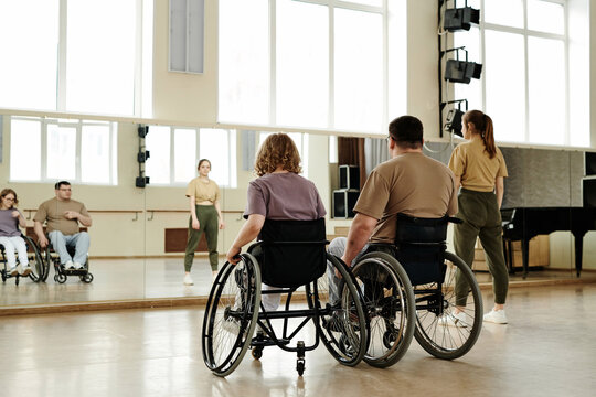 Rear view diverse people practicing dance with wheelchairs in front of mirror in studio, long shot