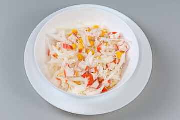 Salad of crab sticks, napa cabbage and corn in bowl