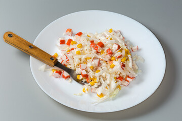 Salad of crab sticks with vegetables on dish with fork