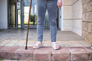Senior woman on a rehabilitation after surgery with walking cane outdoors.