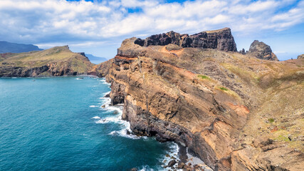 The view of the Madeira coastline, where the vast ocean meets towering cliffs under a sky adorned...