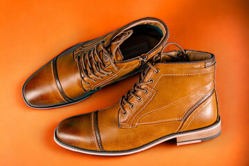 A pair of premium calfskin boots on an orange background. Horizontal shot.