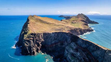 A picturesque coastal landscape in Madeira. Visible are houses surrounded by greenery, mountains, and the azure sea. The harmony of nature and human habitation.