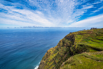 Fototapeta na wymiar The view of the Madeira coastline, where the vast ocean meets towering cliffs under a sky adorned with wispy clouds. Nature in Madeira delights with its harmonious blend of land, water, and sky.
