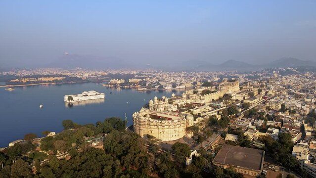 An aerial view of Lake Pichola with a City Palace view in Udaipur in the morning. The city, famously known as the "City of Lakes," is situated amidst the Aravalli Range. Udaipur, Rajasthan, India. 4k 