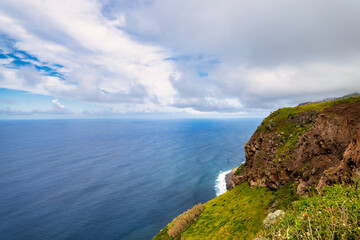 A picturesque coastal landscape in Madeira. Visible are houses surrounded by greenery, mountains, and the azure sea. The harmony of nature and human habitation.