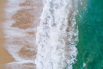 foam from the waves on the shore of a beach, aerial view with a drone