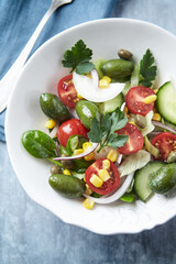 Simple Salad with Green Olives, Cucumber, Cherry Tomatoes and Capers. Bright wooden background. Top view.	