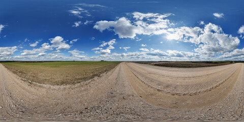 hdri 360 panorama on gravel road among fields in spring evening with awesome clouds in...