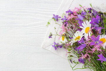 A bouquet of wildflowers lie on a white wooden surface