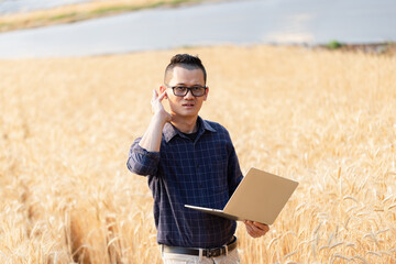 Naklejka na ściany i meble Farmer with digital laptop checking quality in barley fields, Smart farming,