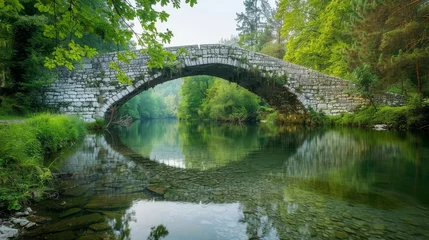 Fotobehang An old stone bridge over a tranquil river in the countryside © Narmina