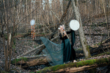Wild Woman Playing Shamanic Drum Standing On Green Moss Tree Trunk In Forest Bushes