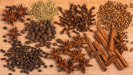 Spices - cloves, peppercorns, star anise, cinnamon sticks, rosemary, coriander are scattered on a...