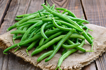 Fresh green beans on a wooden background and table, representing healthy organic produce from the market, ideal for vegetarian diets and nutrition