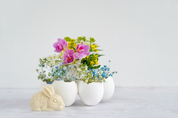 Beautiful Easter composition. flowers in eggs shells and easter bunny figurine on marble background. festive spring season. table decor for Easter holiday, Ostara sabbat. - obrazy, fototapety, plakaty