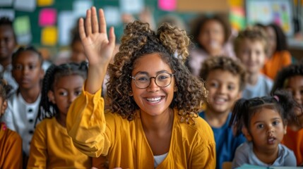 Fototapeta premium Happy children and educator raising hands up sitting at table in modern classroom. Website header with group portrait of cheerful school teacher and first grade students having fun activities in class
