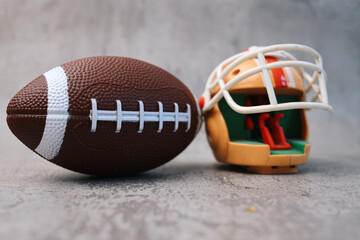 American Football and Rugby Helmet on Grey Cement Background