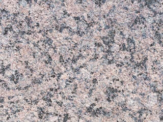Granite texture. Natural pink granite with a grainy pattern. Stone background. Solid rough surface of rock. Durable construction and decoration material. Close-up.