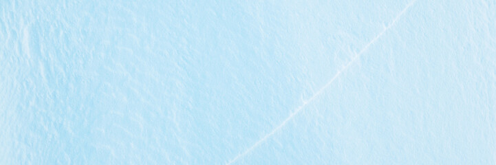 Wide panoramic winter background with snowy ground. Natural snow texture. Wind sculpted patterns on snow surface. Closeup top view with copy space.