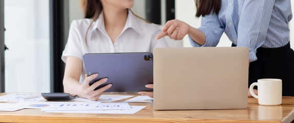 Two young asian business workers using touchpad reading document working at office.