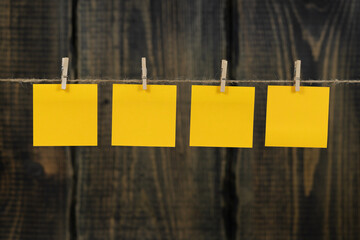 Clothespins with blank notepaper on twine against wooden background space for text. note blank...