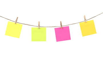 Wooden clothespins with blank notepapers on twine against isolated white background space for text. note blank color paper cards on rope. blanks for designers