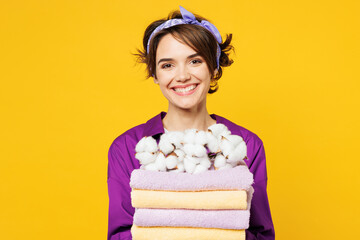 Close up young happy cheerful woman wears purple shirt do housework tidy up hold in hand pile of...