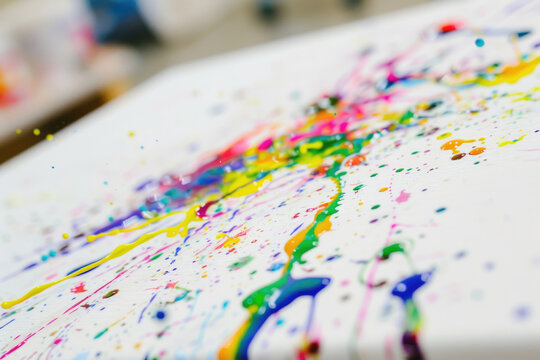 A close-up photo of a colorful paint splatter on a white canvas