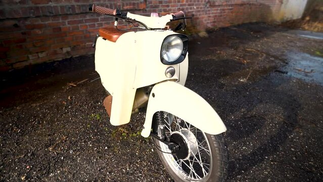 Awesome tracking shot of a scooter in front of a brick wall.