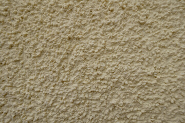 Macro of wall with coarse light beige roughcast finish