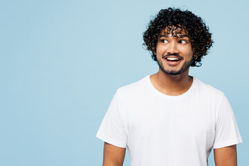 Young fun impressed surprised shocked happy Indian man he wear white t-shirt casual clothes look aside on area isolated on plain pastel light blue cyan background studio portrait. Lifestyle concept. - obrazy, fototapety, plakaty