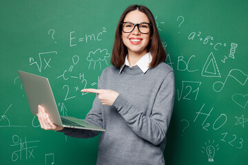 Young smart IT teacher woman wear grey casual shirt glasses use point finger on laptop pc computer...