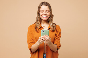 Young smiling happy fun Caucasian woman she wearing orange shirt casual clothes hold in hand use...