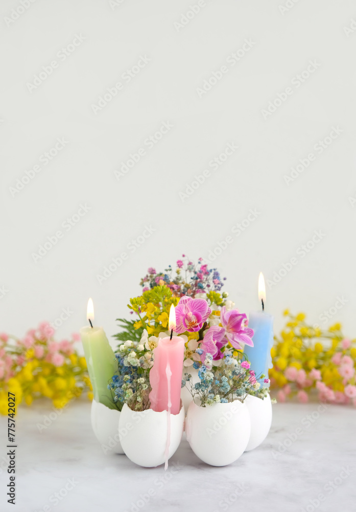 Wall mural Beautiful Easter composition. Burning candles and flowers in eggs shells on table background. festive spring season. table decor for Easter holiday, Ostara sabbat.