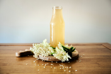 Taste of spring with a front view Elderflower cordial on wooden table surrounded by white...