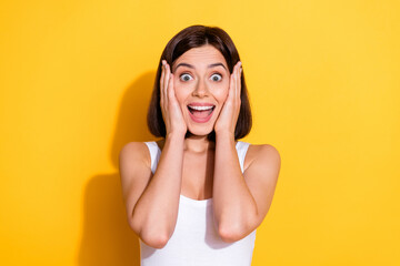 Photo portrait of attractive young girl touch cheeks shocked wear trendy white outfit isolated on yellow color background