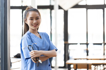 Asian female doctor with blue coat and holding stethoscope in hospital.