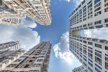 view from below into blue sky with clouds of large modern skyscraper residential complex with arch