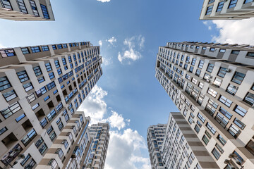 view from below into blue sky with clouds of large modern skyscraper residential complex with arch