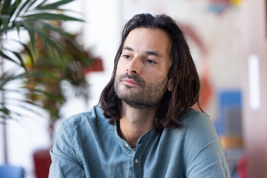 Portrait d'un bel homme de 30 ans qui travaille dans un bureau. il a les cheveux longs et une barbe